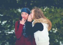 woman whispering secret to another woman