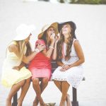 women laughing on bench in beach