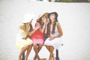 women laughing on bench in beach