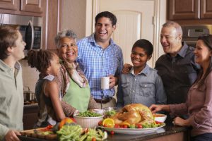 Diverse family in home kitchen cooking Thanksgiving dinner.