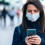 Woman with face protective mask using phone