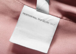 Care instructions clothing label on pink textile background closeup