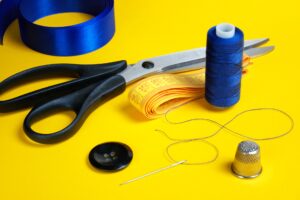 tailor's scissors, needle, thread, thimble, button, ribbon